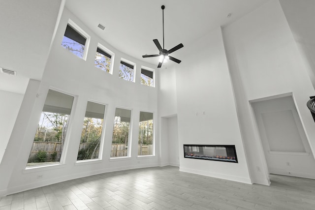 unfurnished living room with ceiling fan and a high ceiling