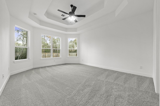 carpeted empty room with ceiling fan and a raised ceiling