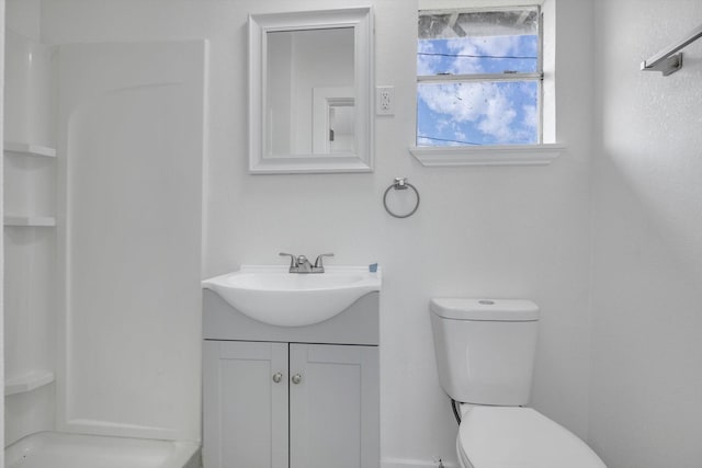 bathroom featuring toilet, walk in shower, and vanity