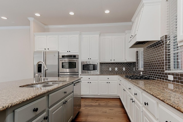 kitchen with white cabinetry, stainless steel appliances, light stone counters, and sink