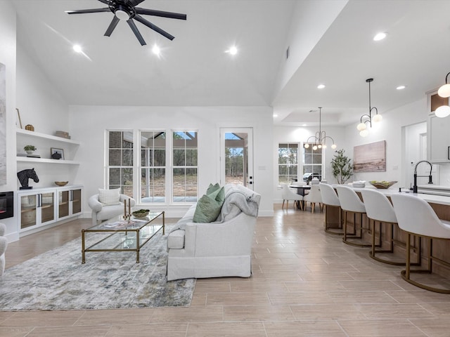 living room with ceiling fan with notable chandelier and high vaulted ceiling