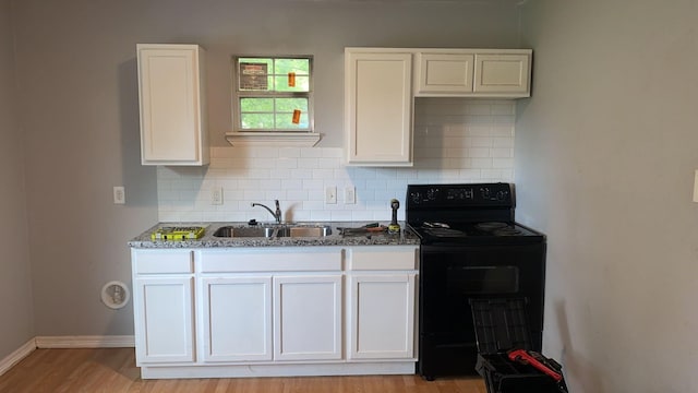 kitchen featuring sink, black electric range, white cabinets, decorative backsplash, and dark stone counters