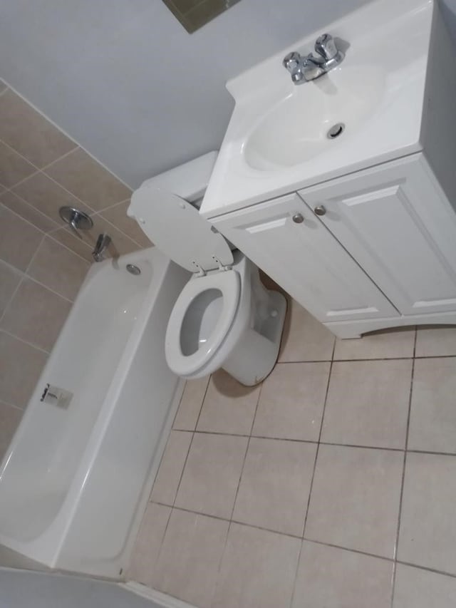 bathroom featuring tile patterned flooring, vanity, a tub, and toilet