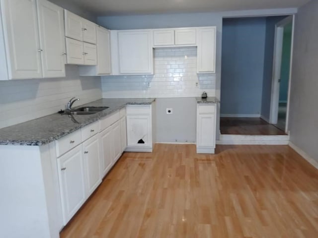 kitchen with stone countertops, sink, white cabinets, and light hardwood / wood-style flooring