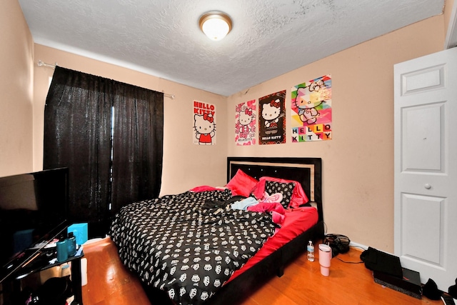 bedroom with a textured ceiling and hardwood / wood-style floors