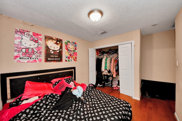 bedroom with hardwood / wood-style floors, a closet, and a textured ceiling