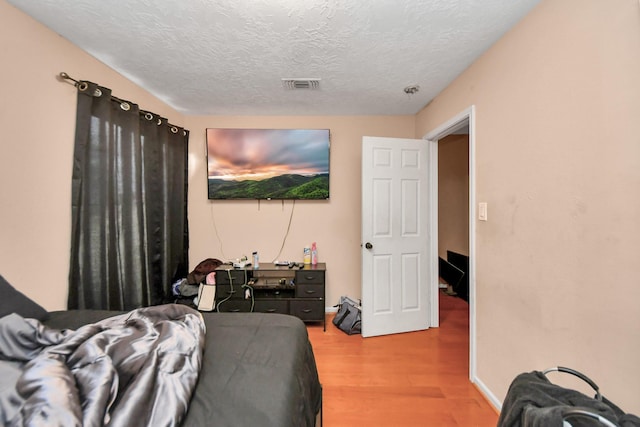 bedroom with a textured ceiling and hardwood / wood-style flooring