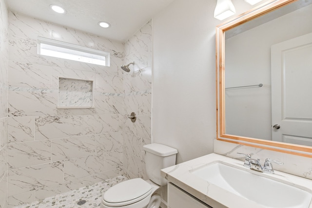 bathroom featuring vanity, toilet, and a tile shower