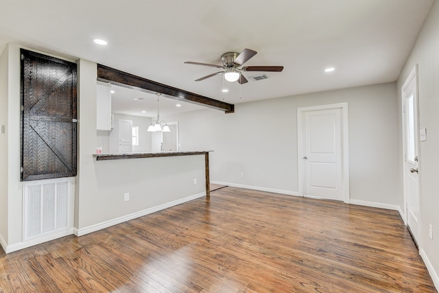 empty room with hardwood / wood-style flooring, ceiling fan with notable chandelier, and beam ceiling