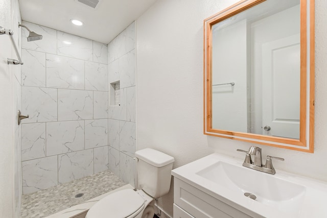 bathroom featuring toilet, vanity, and tiled shower