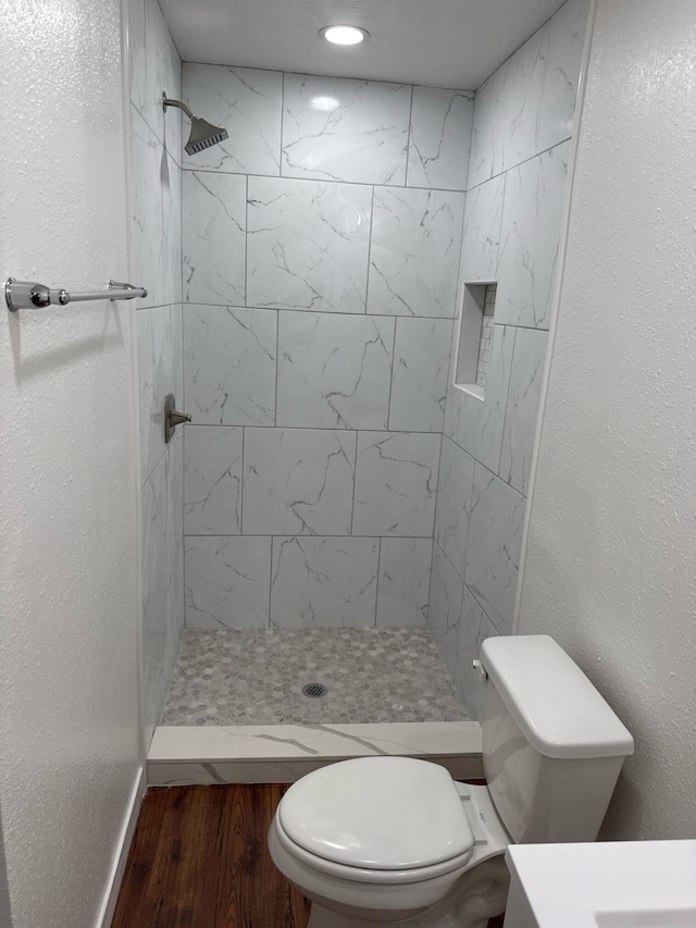 bathroom featuring vanity, toilet, a tile shower, and hardwood / wood-style flooring