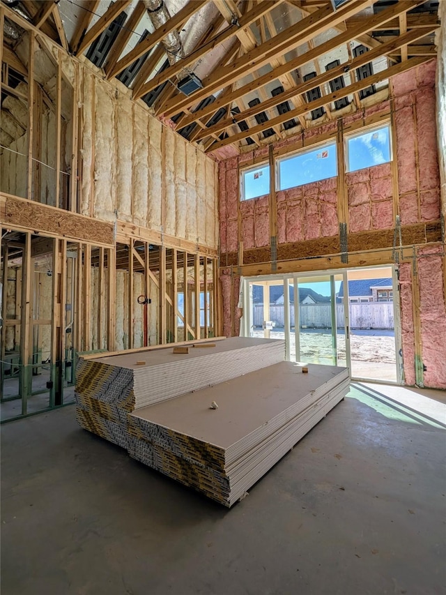 miscellaneous room featuring concrete floors, a water view, and a high ceiling