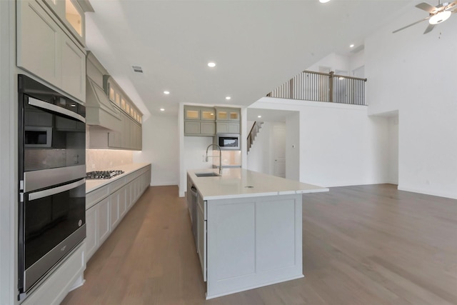 13115 Brookwood Bend Ln, Conroe, TX 77302 - kitchen with appliances with stainless steel finishes, light wood-style floors, a sink, a kitchen island with sink, and recessed lighting