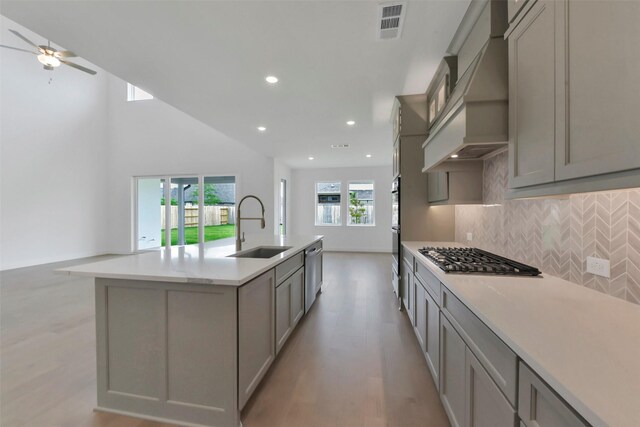 13115 Brookwood Bend Ln, Conroe, TX 77302 - kitchen featuring a sink, stainless steel appliances, gray cabinets, custom range hood, and backsplash