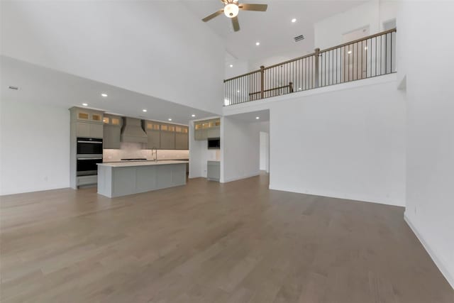 13115 Brookwood Bend Ln, Conroe, TX 77302 - unfurnished living room with a ceiling fan, light wood-style flooring, a towering ceiling, and recessed lighting