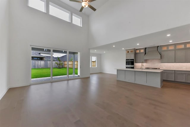 13115 Brookwood Bend Ln, Conroe, TX 77302 - unfurnished living room with ceiling fan, wood finished floors, a towering ceiling, a sink, and recessed lighting