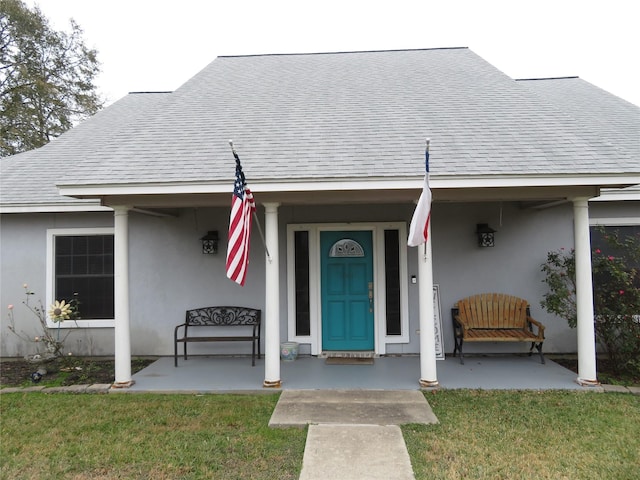 property entrance with covered porch and a lawn