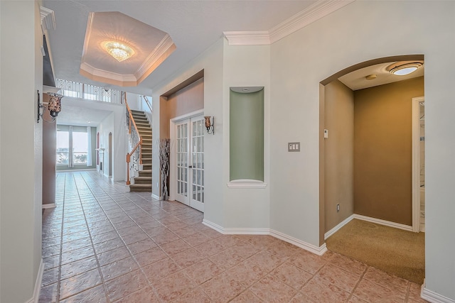 hall with french doors, crown molding, light carpet, and a raised ceiling