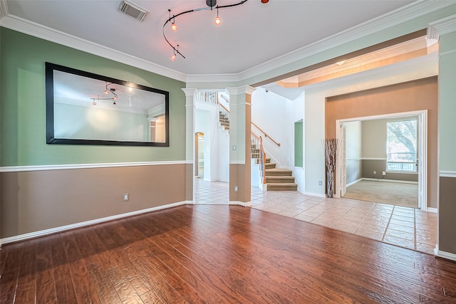 empty room featuring light wood-type flooring, crown molding, rail lighting, and decorative columns