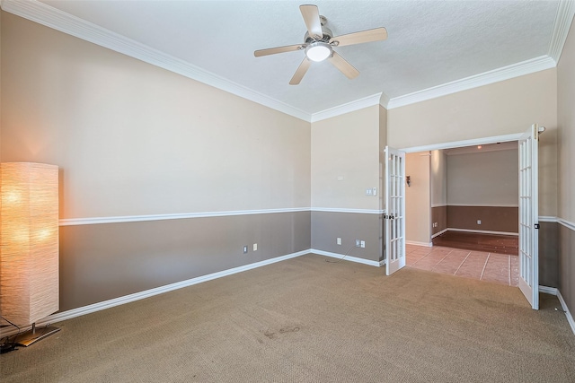 carpeted spare room featuring ceiling fan, french doors, and crown molding