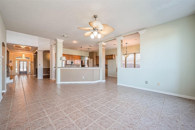 unfurnished living room with ceiling fan with notable chandelier and light tile patterned floors