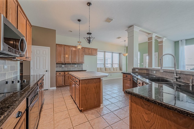 kitchen with black appliances, a kitchen island, decorative light fixtures, backsplash, and decorative columns