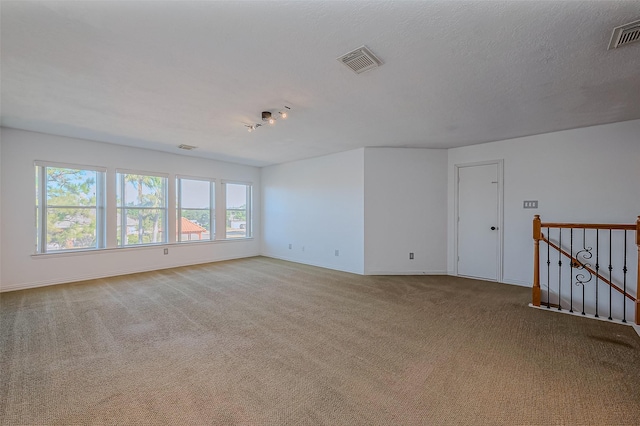 spare room with light carpet and a textured ceiling