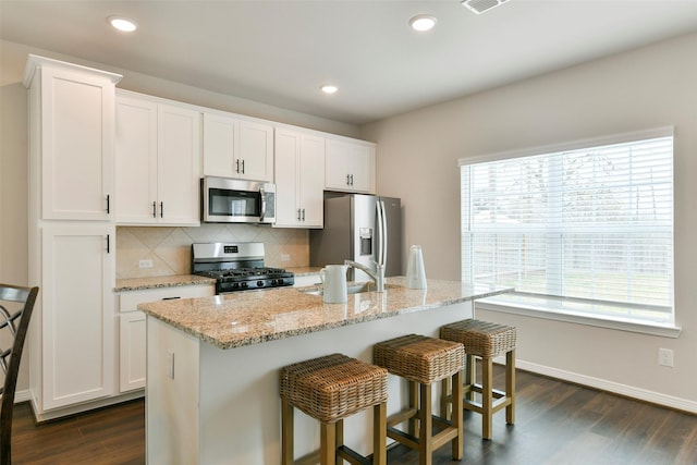 kitchen featuring stainless steel appliances, an island with sink, white cabinetry, and sink