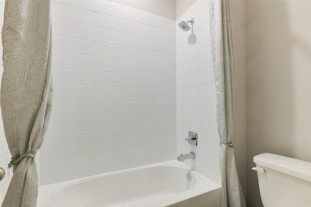 bathroom with toilet and tiled shower / bath