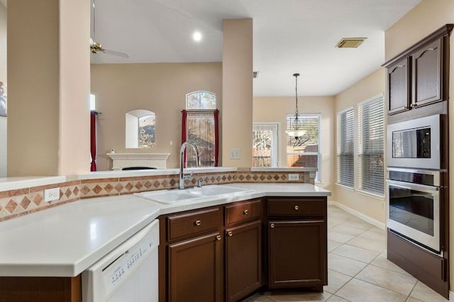 kitchen featuring pendant lighting, sink, light tile patterned floors, white dishwasher, and dark brown cabinetry