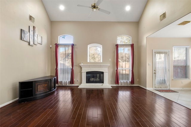 unfurnished living room featuring a towering ceiling, wood-type flooring, and ceiling fan