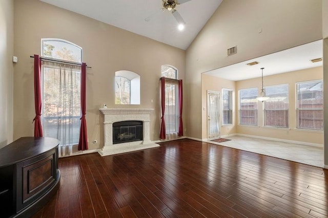 unfurnished living room with hardwood / wood-style flooring, ceiling fan, high vaulted ceiling, and a wealth of natural light