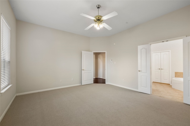 unfurnished bedroom with multiple windows, ceiling fan, connected bathroom, and light carpet