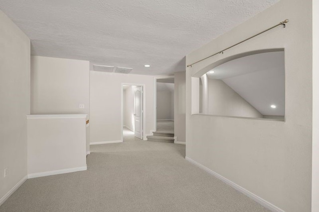 carpeted empty room with vaulted ceiling and a textured ceiling