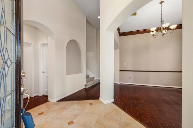 foyer featuring an inviting chandelier, light tile patterned floors, and crown molding