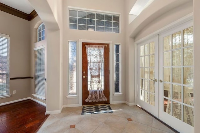 foyer entrance with crown molding, plenty of natural light, and french doors