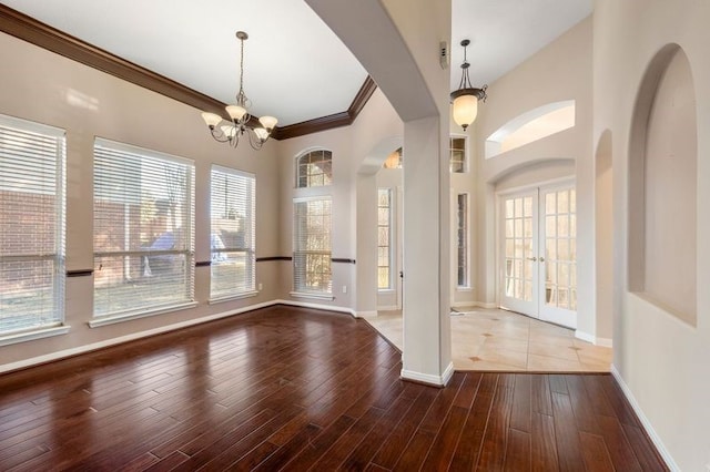 foyer with ornamental molding, hardwood / wood-style floors, a chandelier, and french doors