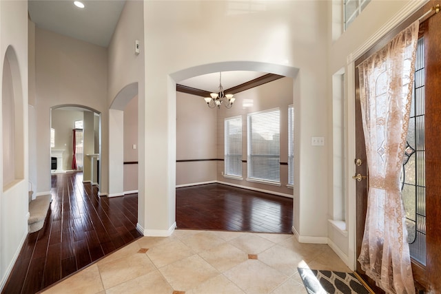 foyer featuring crown molding, a healthy amount of sunlight, a chandelier, and light tile patterned floors