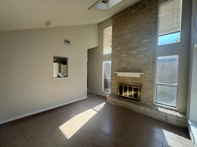 unfurnished living room featuring dark tile patterned floors, high vaulted ceiling, a brick fireplace, and a textured ceiling