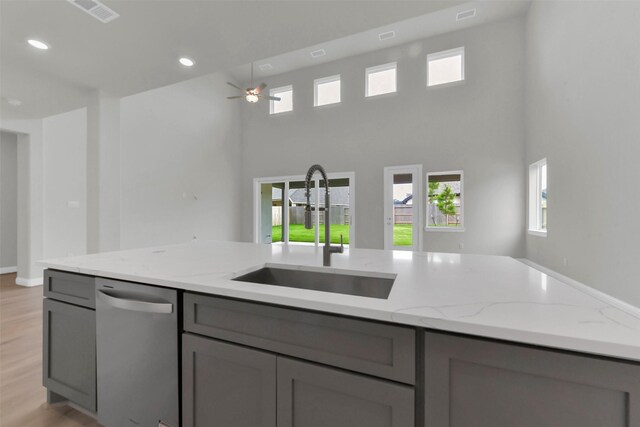 16163 Sheridan River Trl, Conroe, TX 77302 - kitchen with a sink, gray cabinets, stainless steel dishwasher, light stone counters, and a ceiling fan