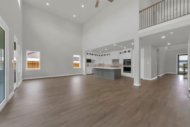 16163 Sheridan River Trl, Conroe, TX 77302 - unfurnished living room with a high ceiling, a ceiling fan, a sink, baseboards, and dark wood-type flooring