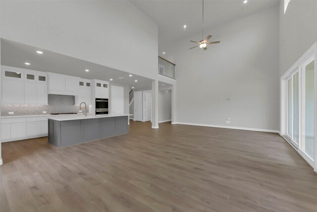 16163 Sheridan River Trl, Conroe, TX 77302 - kitchen featuring a high ceiling, open floor plan, white cabinets, a center island with sink, and ceiling fan