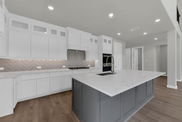 16163 Sheridan River Trl, Conroe, TX 77302 - kitchen with a sink, an island with sink, tasteful backsplash, white cabinets, and stainless steel double oven