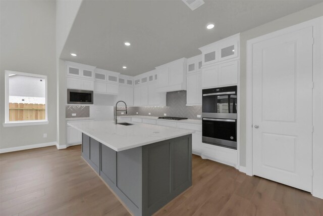 16163 Sheridan River Trl, Conroe, TX 77302 - kitchen with appliances with stainless steel finishes, a sink, tasteful backsplash, white cabinetry, and wood finished floors