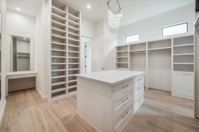 walk in closet with light wood-type flooring and an inviting chandelier