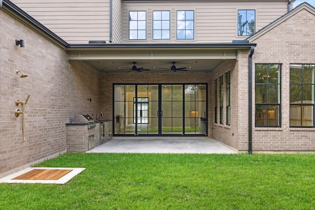 view of exterior entry with a patio area, ceiling fan, a yard, and area for grilling