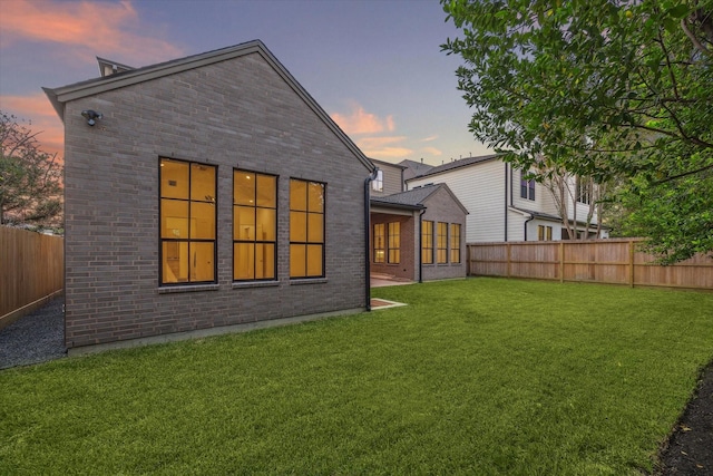 back house at dusk with a lawn