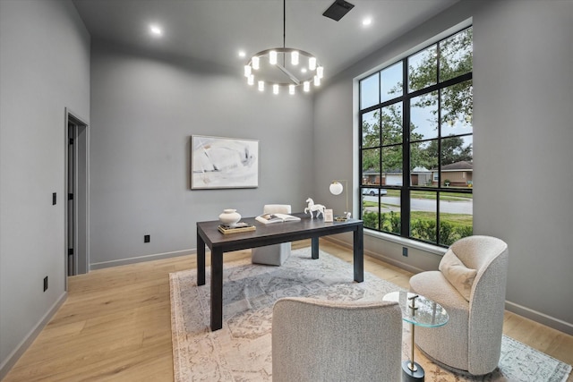 office space featuring a chandelier, light hardwood / wood-style floors, and a high ceiling