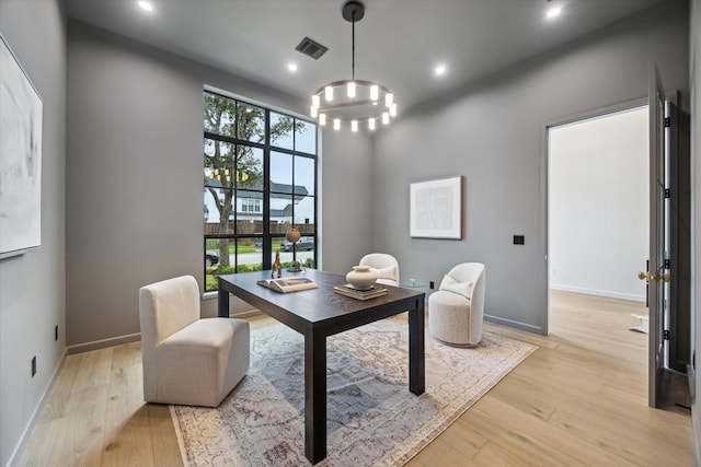 office with light wood-type flooring and a chandelier