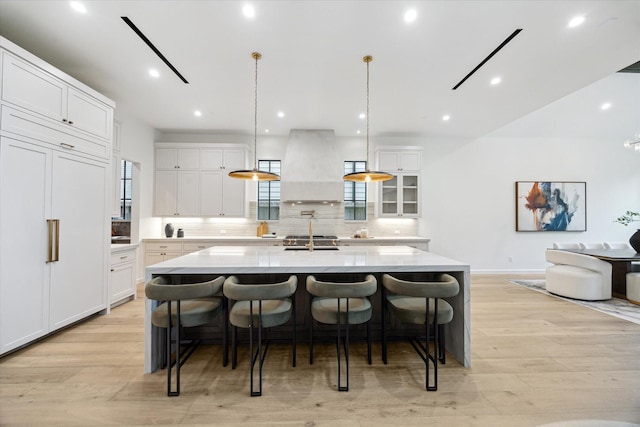 kitchen with white cabinetry, a spacious island, and wall chimney range hood